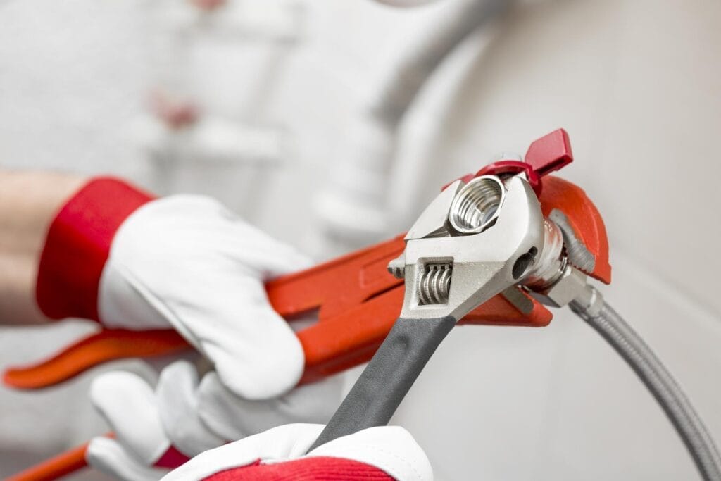 Plumber holding pipe wrenches for an emergency repair in West Valley City