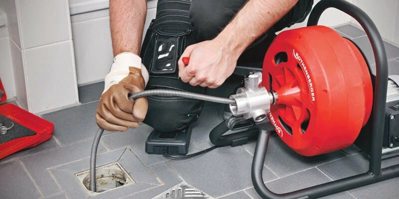 Plumber using a drain-cleaning machine in West Valley City
