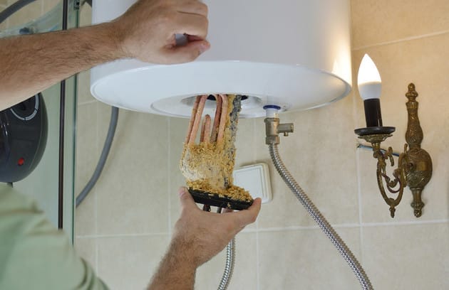 Technician removing mineral buildup from a water heater in West Valley City