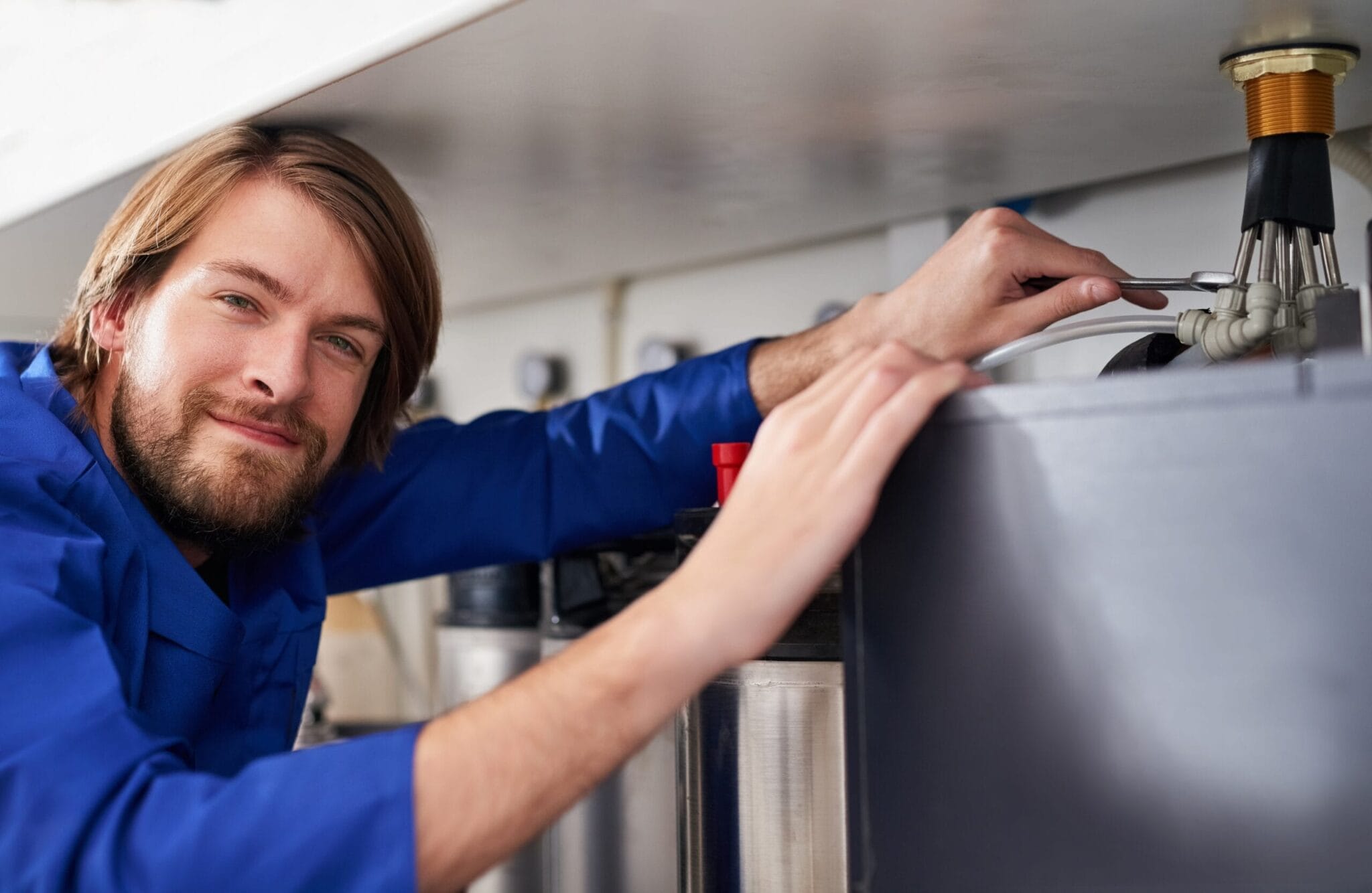 Technician servicing a residential water heater tank in West Valley City