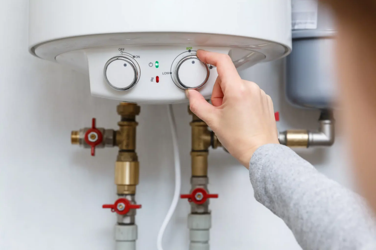 Homeowner adjusting the temperature controls on a water heater in West Valley City
